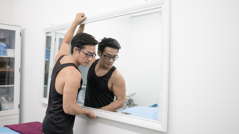 người đàn ông treo gương lên tường