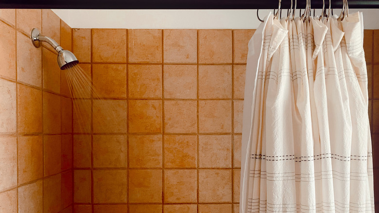 rèm tắm có móc với vòi sen đang chảy ở nền