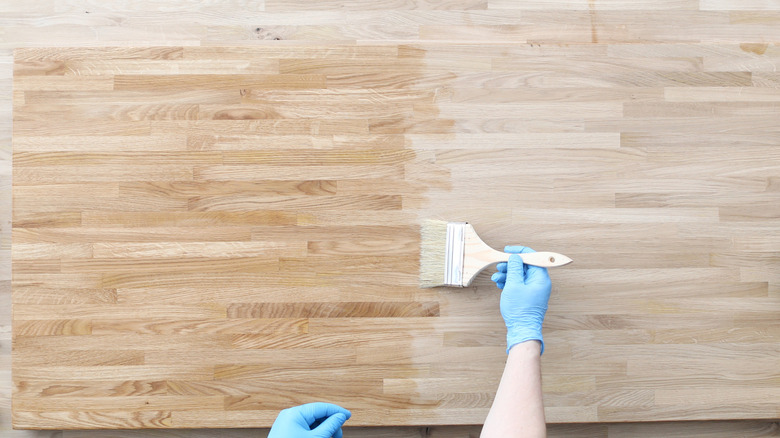 kính tươi được áp dụng cho gỗ sồi với bàn tay đeo găng