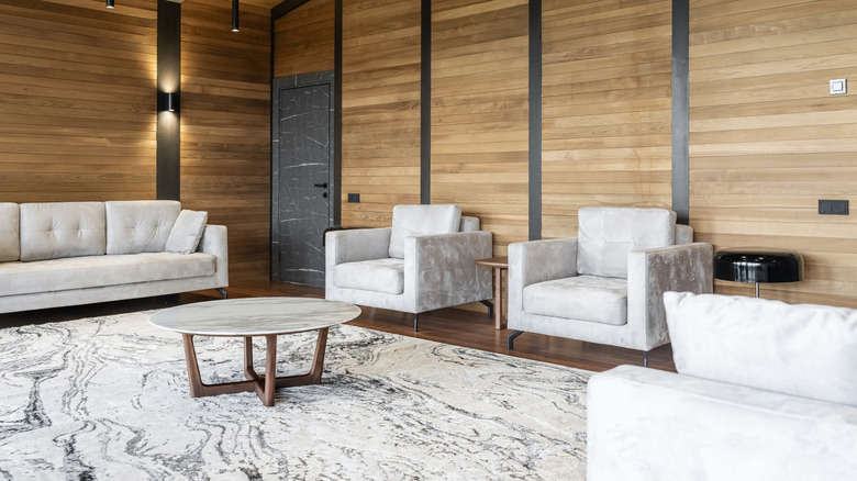 Phòng khách trông hiện đại với đồ nội thất màu xám phù hợp, tường ván bằng gỗ