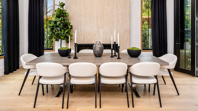 Phòng ăn hiện đại với bàn ăn bằng gỗ và chrome được bao quanh bởi những chiếc ghế ăn ở bọc kem với khung màu đen