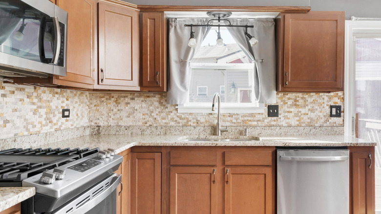 Nhà bếp lỗi thời với rèm trắng, tủ gỗ, quầy gỗ, gạch lát gạch,