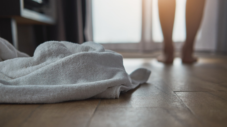 Khăn trắng trên sàn phòng tắm với đôi chân mờ ở phía sau