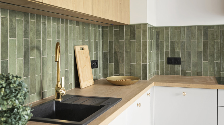 Một tấm gạch tàu điện ngầm màu xanh lá cây mộc mạc của nhà bếp mộc mạc với các điểm nhấn kim loại