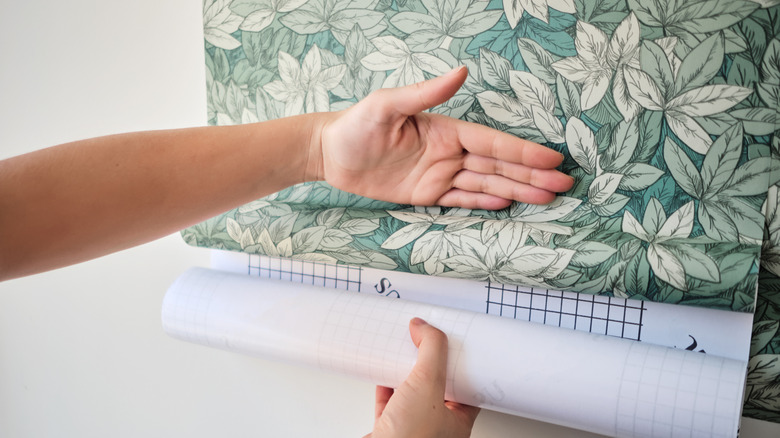 Bàn tay làm mịn vỏ lá xanh và dán hình nền vào tường