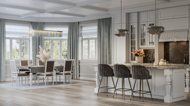 Khu vực sinh hoạt và ăn uống khái niệm mở với đèn chùm tuyến tính lớn trên bàn ăn và mặt dây thủy tinh hun khói hình học trên đảo