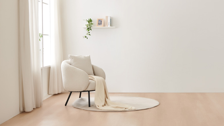 Phòng có tường kem, kem lót xung quanh cửa sổ, ghế boucle kem với ném, và một tấm thảm kem trên sàn màu be
