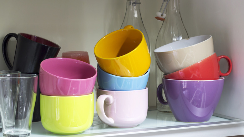 Một loạt các cốc cà phê đầy màu sắc xếp chồng lên nhau trong tủ
