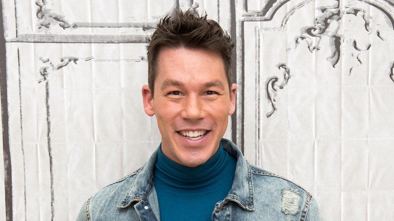David Bromstad mỉm cười trước một nền vải trắng.