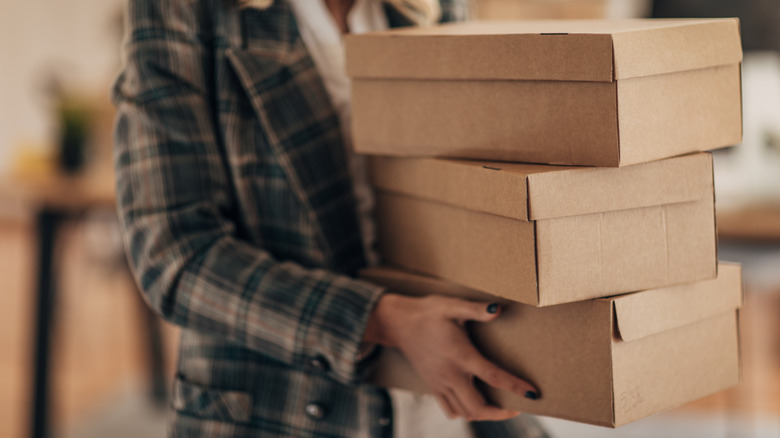 Người phụ nữ cầm hộp đựng giày bằng bìa cứng màu nâu
