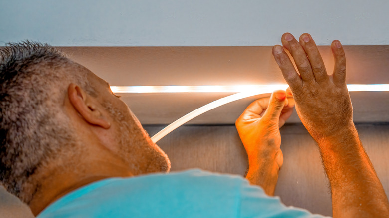 người đàn ông cài đặt dải đèn LED