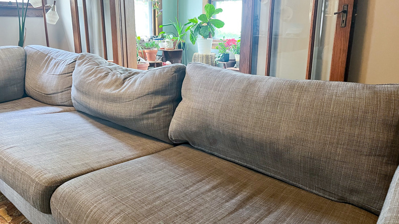 ghế sofa màu xám trong phòng khách nơi một chiếc đệm được nhồi đúng cách trong khi hai cái còn lại bị chùng xuống