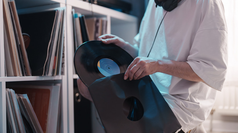 Người đặt Vinyl LP trở lại tay áo trước kho lưu trữ đầy đủ các bản ghi