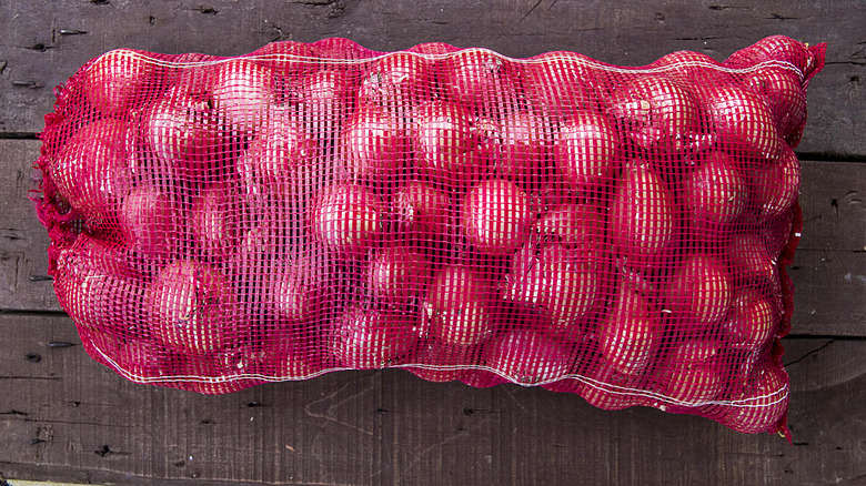 Túi lưới hành tây trên bàn gỗ