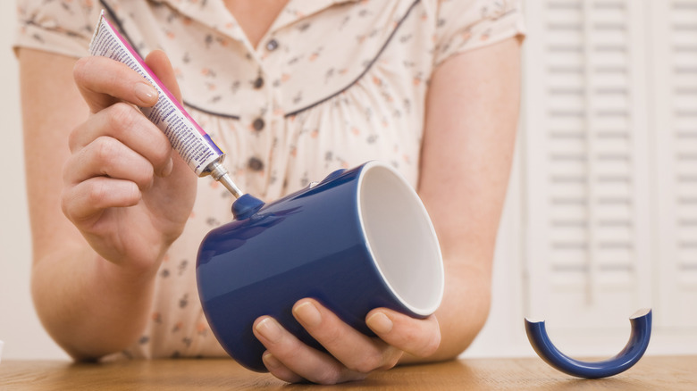 Người phụ nữ dán tay cầm trên cốc màu xanh