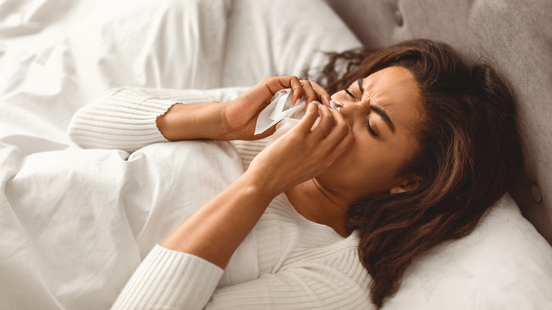 Một người phụ nữ cầm khăn giấy vào mũi