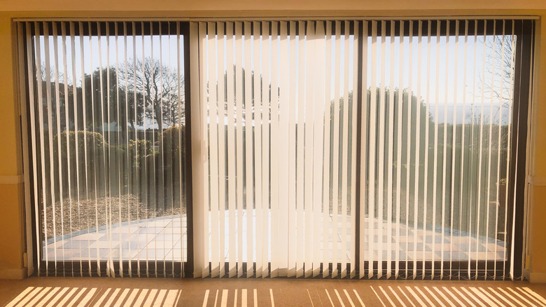 Mở rèm dọc trên cửa kính trượt với ánh nắng mặt trời chiếu qua