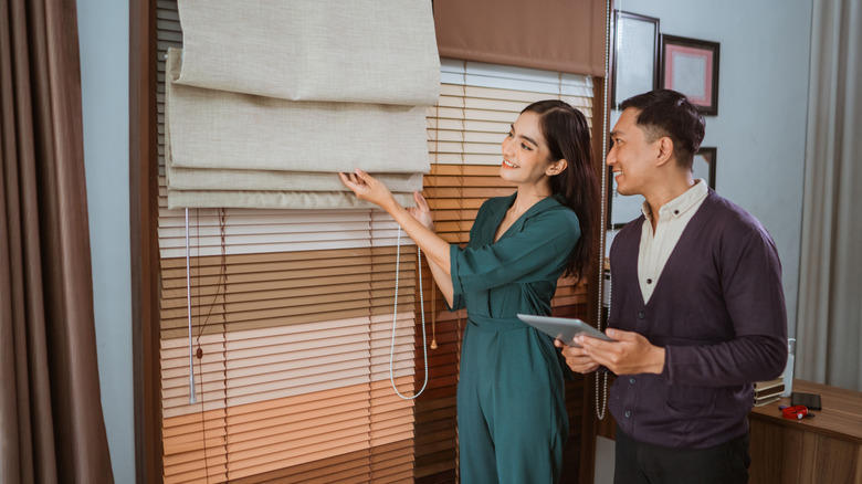 Cặp đôi mua sắm cho các phương pháp điều trị cửa sổ và nhìn vào một sắc thái La Mã dệt