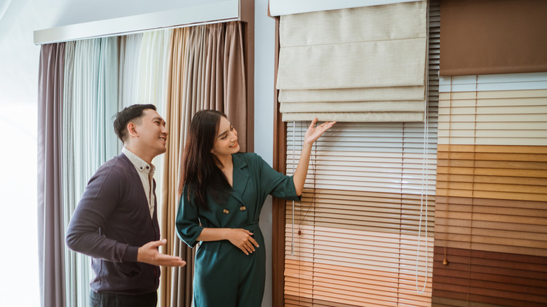 Cặp đôi mua sắm cho các phương pháp điều trị cửa sổ và nhìn vào một sắc thái La Mã