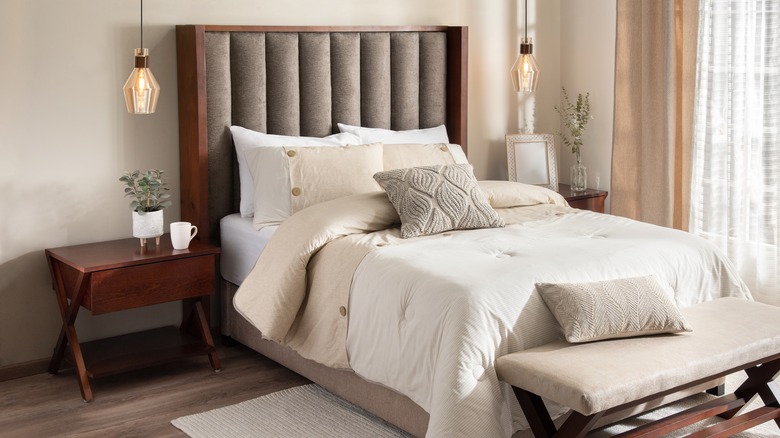 Tủ đầu giường bằng gỗ cạnh giường với ga trải giường màu be