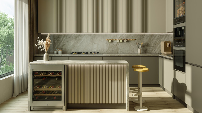 nhà bếp hiện đại với tủ có rãnh màu be và tấm ốp tường bằng đá tự nhiên