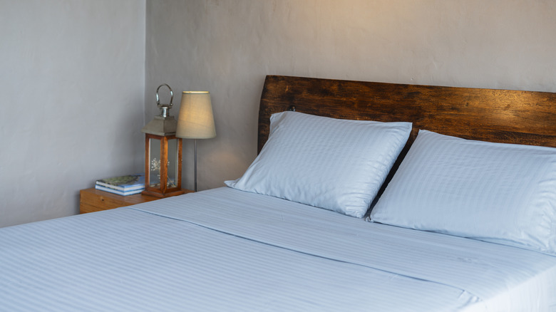 Cận cảnh chiếc giường gỗ được kết hợp với bộ chăn ga gối đệm màu xanh lam phù hợp