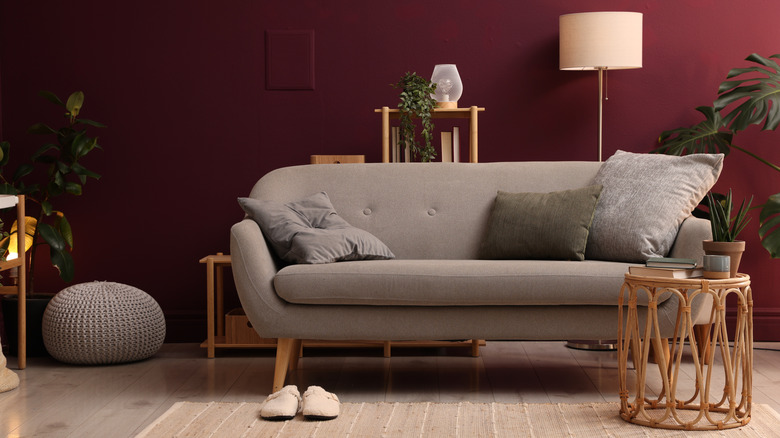 Ghế sofa màu nâu sẫm và đồ nội thất bằng gỗ ấm áp được bố trí một cách nghệ thuật trong phòng khách màu đỏ tía