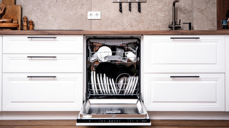 Máy rửa bát dạng mở và bừa bộn trong nhà bếp hiện đại, đầy phong cách với tủ màu trắng và gỗ