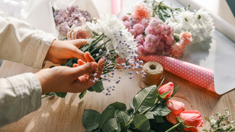 Người cầm hoa trên bàn bằng dây bện để cắm hoa ở giữa