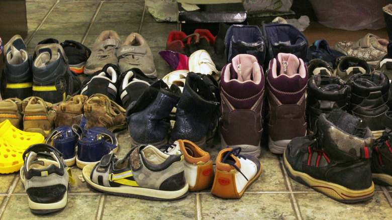 đống giày hỗn loạn trên sàn lát gạch màu xám