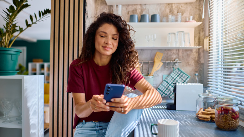 Người phụ nữ nói chuyện điện thoại trong bếp có rèm