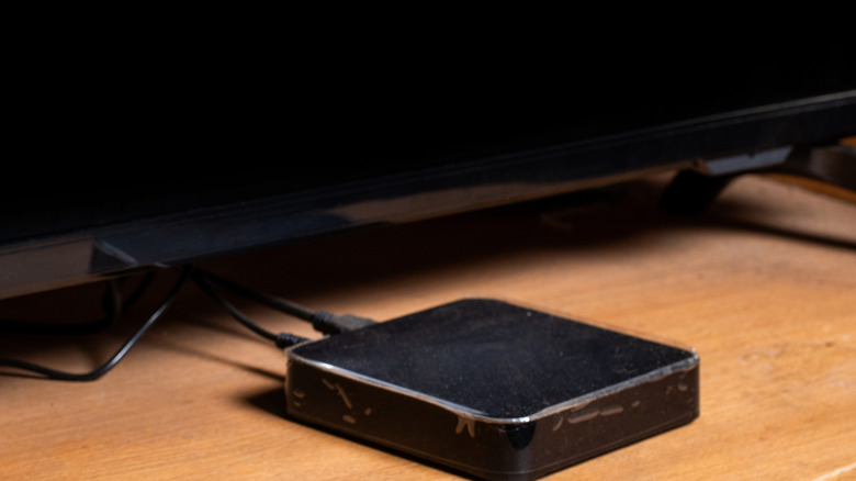 Một hộp phát trực tuyến phương tiện truyền thông nhỏ màu đen điển hình ở phía trước tivi