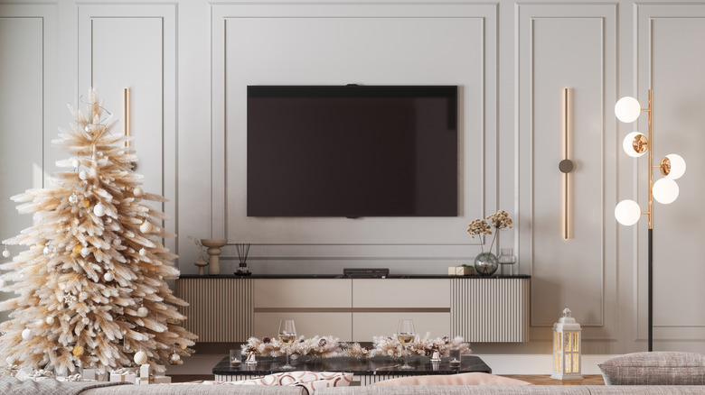 Một chiếc tivi được bao quanh bởi khung tranh trong phòng khách màu trung tính được trang trí cho dịp Giáng sinh