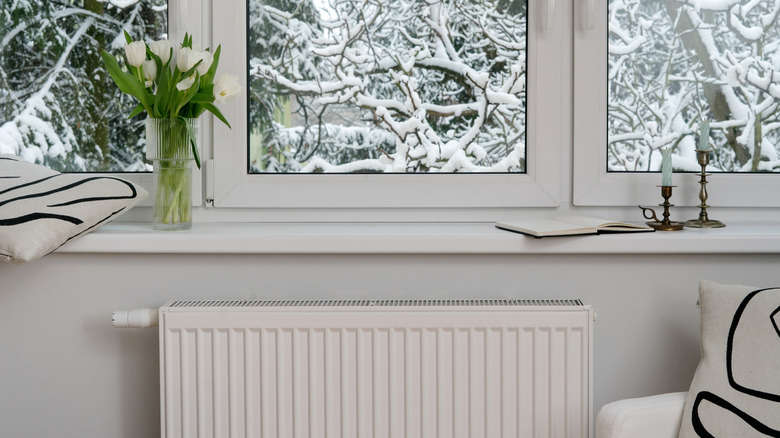 Một bộ tản nhiệt có mái che trong một ngôi nhà có bề ngoài phủ đầy tuyết có thể nhìn thấy qua cửa sổ