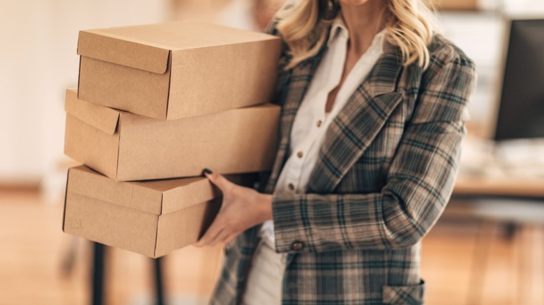 Người mang chồng hộp đựng giày bằng bìa cứng rỗng