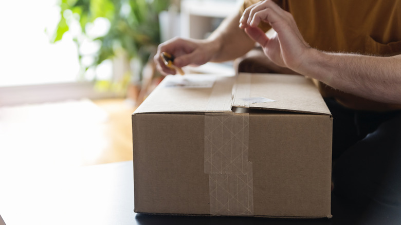 một người đàn ông cắt mở hộp các tông