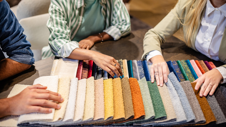 Ba người đang ngắm nhìn các mẫu thảm khác nhau