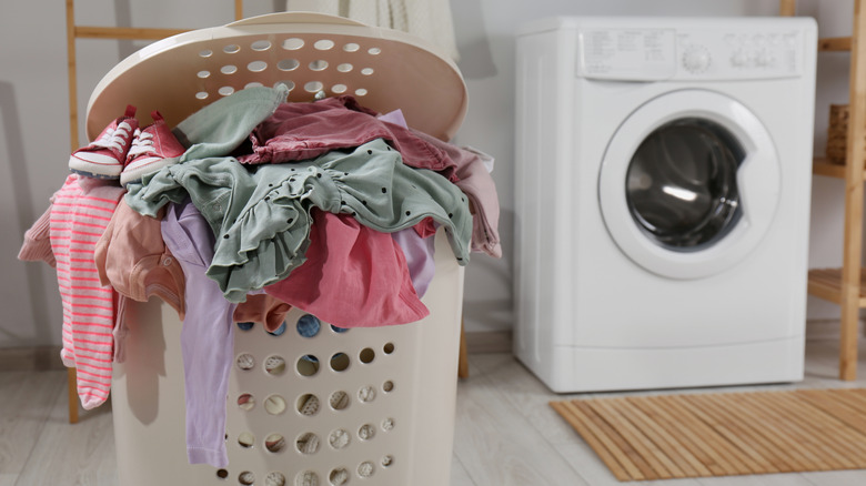 Giỏ đựng đồ giặt đầy đủ bên cạnh máy giặt