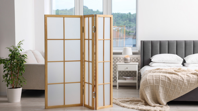 Một tấm bình phong gấp mờ phía trước giường và cửa sổ