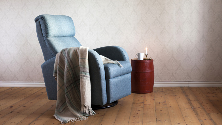 Ghế tựa màu xanh với chăn kẻ sọc trong không gian sống.