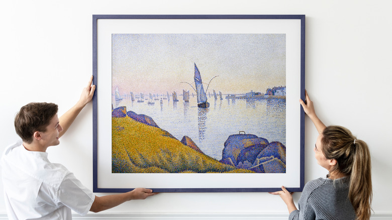 một cặp vợ chồng treo một bức tranh trên tường