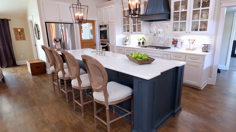 Nhà bếp màu trắng với đảo bếp và máy hút mùi màu xanh đậm