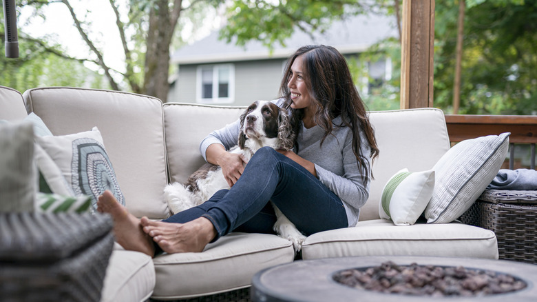 Người phụ nữ ngồi trên ghế hiên với con chó