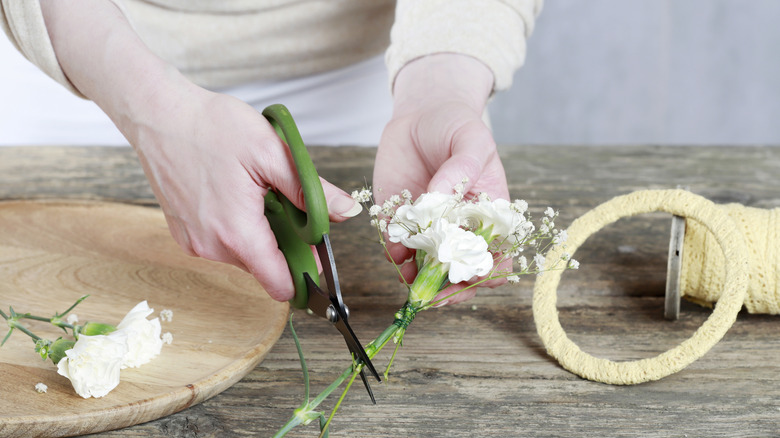 Người phụ nữ cắt cành hoa làm vòng hoa tự chế.
