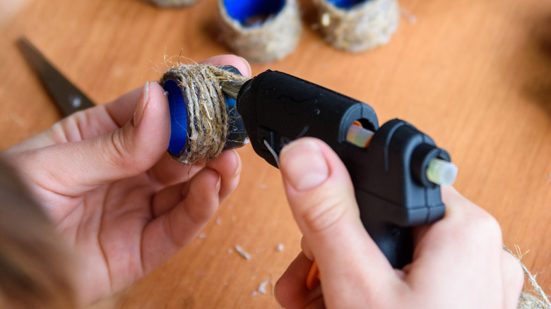 ai đó đang làm đồ thủ công từ sợi xe bằng súng keo nóng