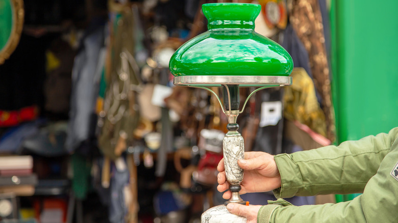 Một người đàn ông cầm chiếc đèn cổ bên ngoài cửa hàng tiết kiệm