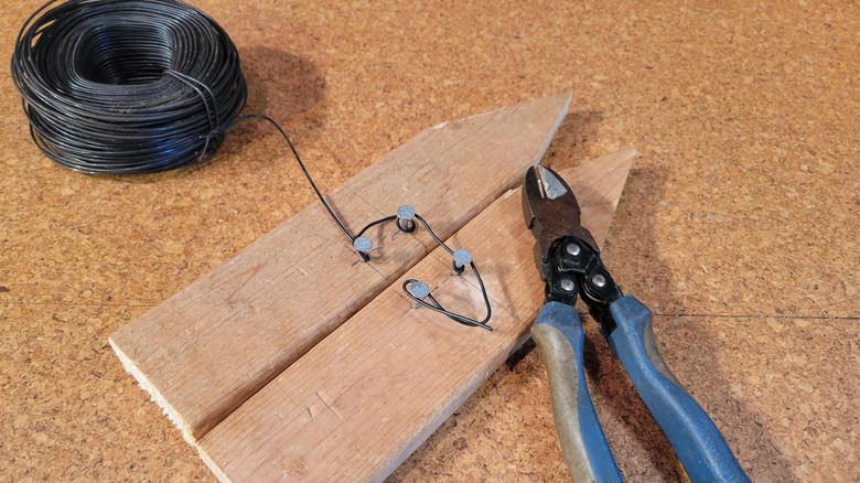 Nối hai tấm ván viền sân vườn bằng dây cột, tạo độ chùng để điều chỉnh trong tương lai