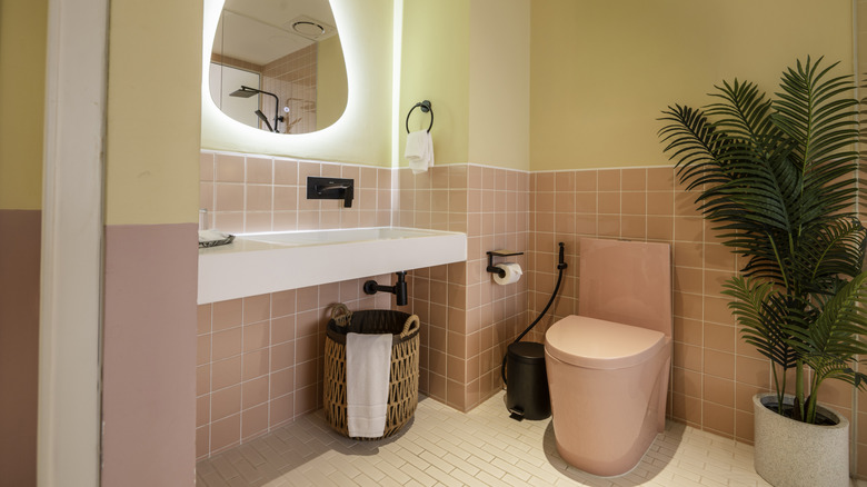 Phòng tắm màu vàng và hồng pastel với bồn cầu màu hồng