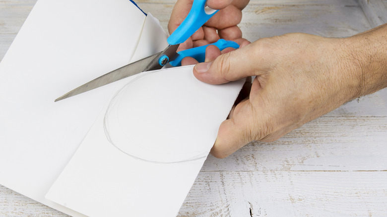 Tay cắt một vòng tròn từ giấy