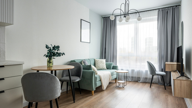 Phòng khách hẹp với đèn chiếu sáng cỡ lớn và rèm từ sàn đến trần